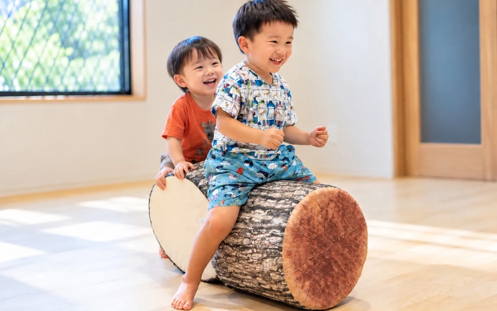 丸太のクッションにまたがって笑い合うふたりのお子さま