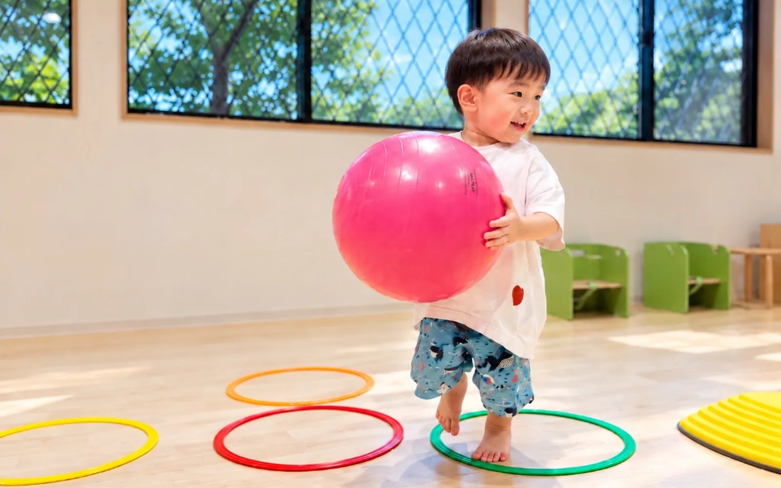大きなピンクのボールを抱えて歩くお子さま